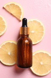 Bottle of cosmetic serum and lemon slices on wet pink background, flat lay