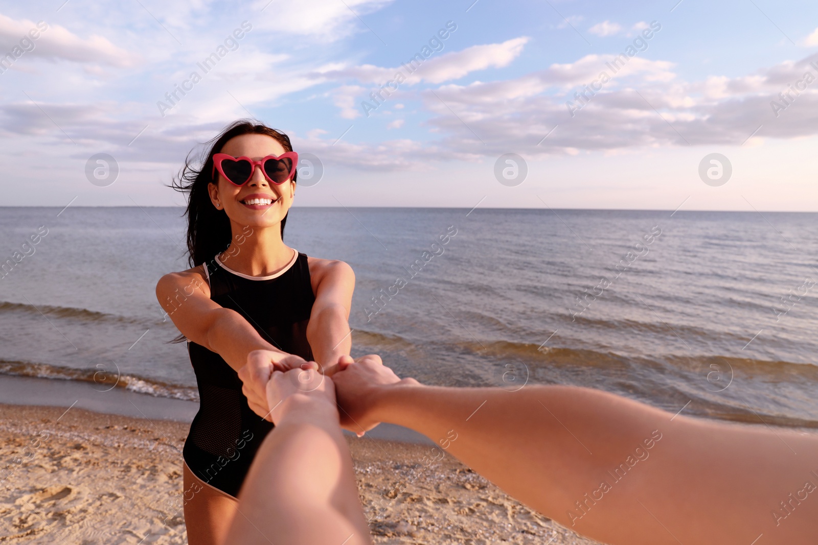 Photo of Young woman holding hands with girlfriend on beach