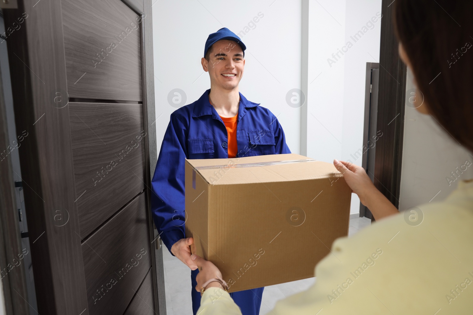 Photo of Woman receiving parcel from courier at home