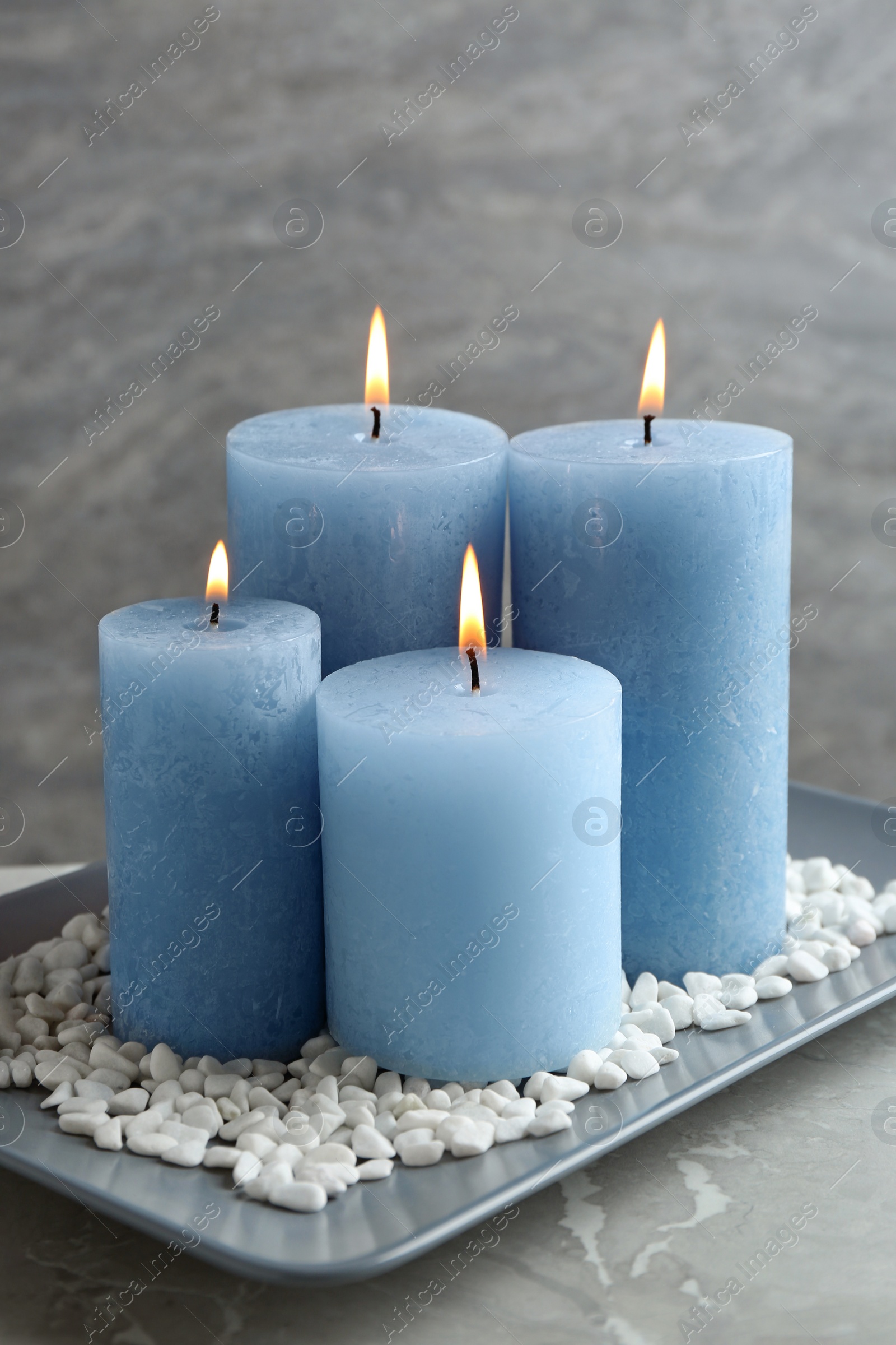 Photo of Plate with burning color candles and rocks on table