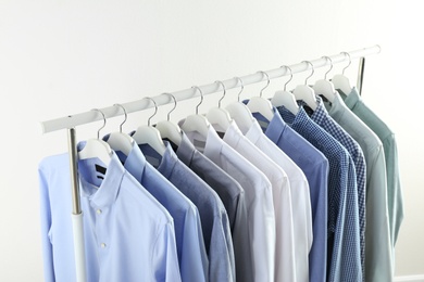 Photo of Men's clothes hanging on wardrobe rack against white background