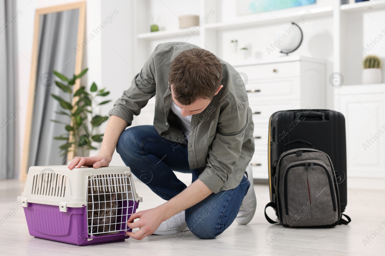 Photo of Travel with pet. Man closing carrier with cat at home