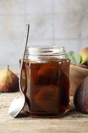 Photo of Jar of tasty sweet jam and fresh figs on wooden table