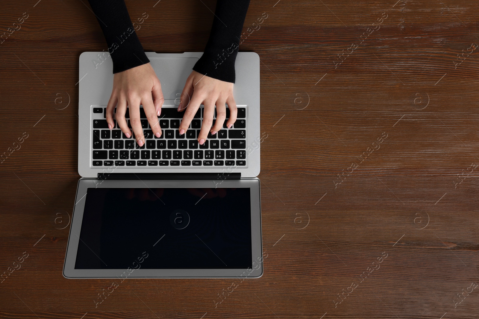 Photo of Woman working with laptop at wooden table, top view. Space for text