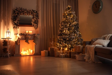 Stylish interior with decorative fireplace and beautiful Christmas tree in evening