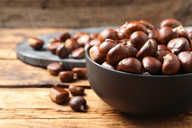 Photo of Fresh sweet edible chestnuts on wooden table, closeup