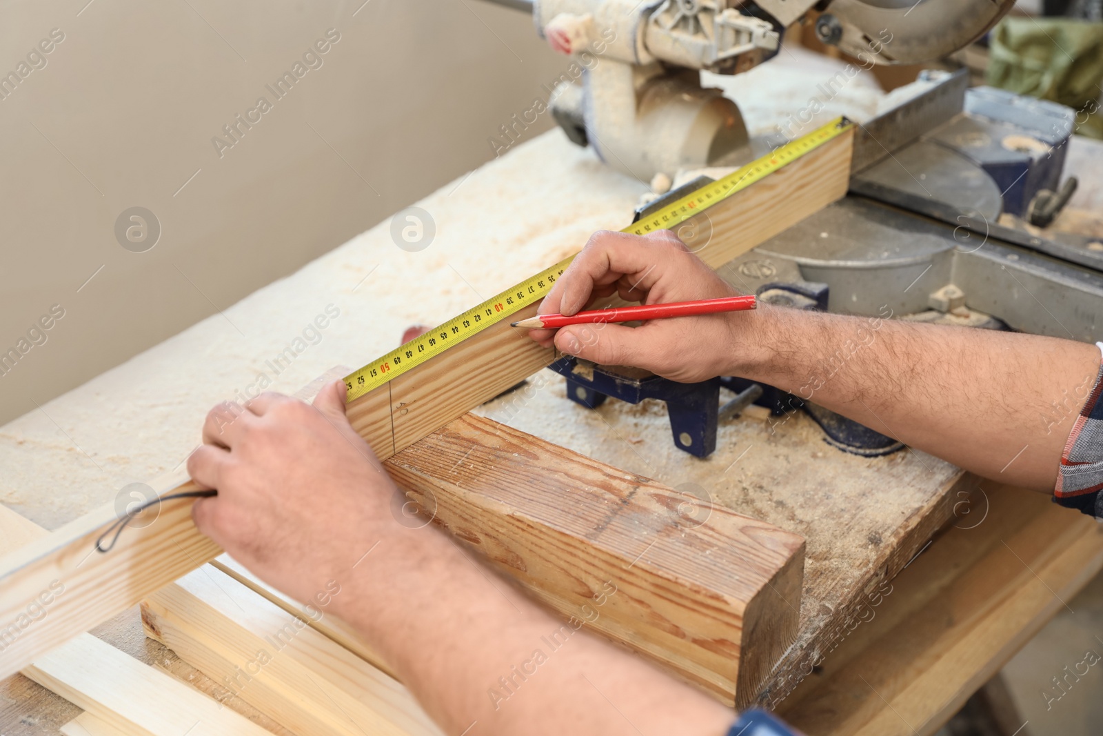 Photo of Working man measuring timber strip in carpentry shop, closeup