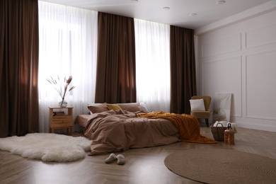 Bed with brown linens in stylish room interior