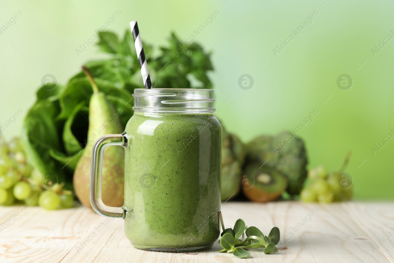 Photo of Mason jar of fresh green smoothie and ingredients on wooden table