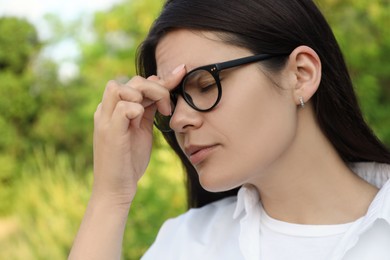 Photo of Young woman suffering from eyestrain outdoors on sunny day, closeup