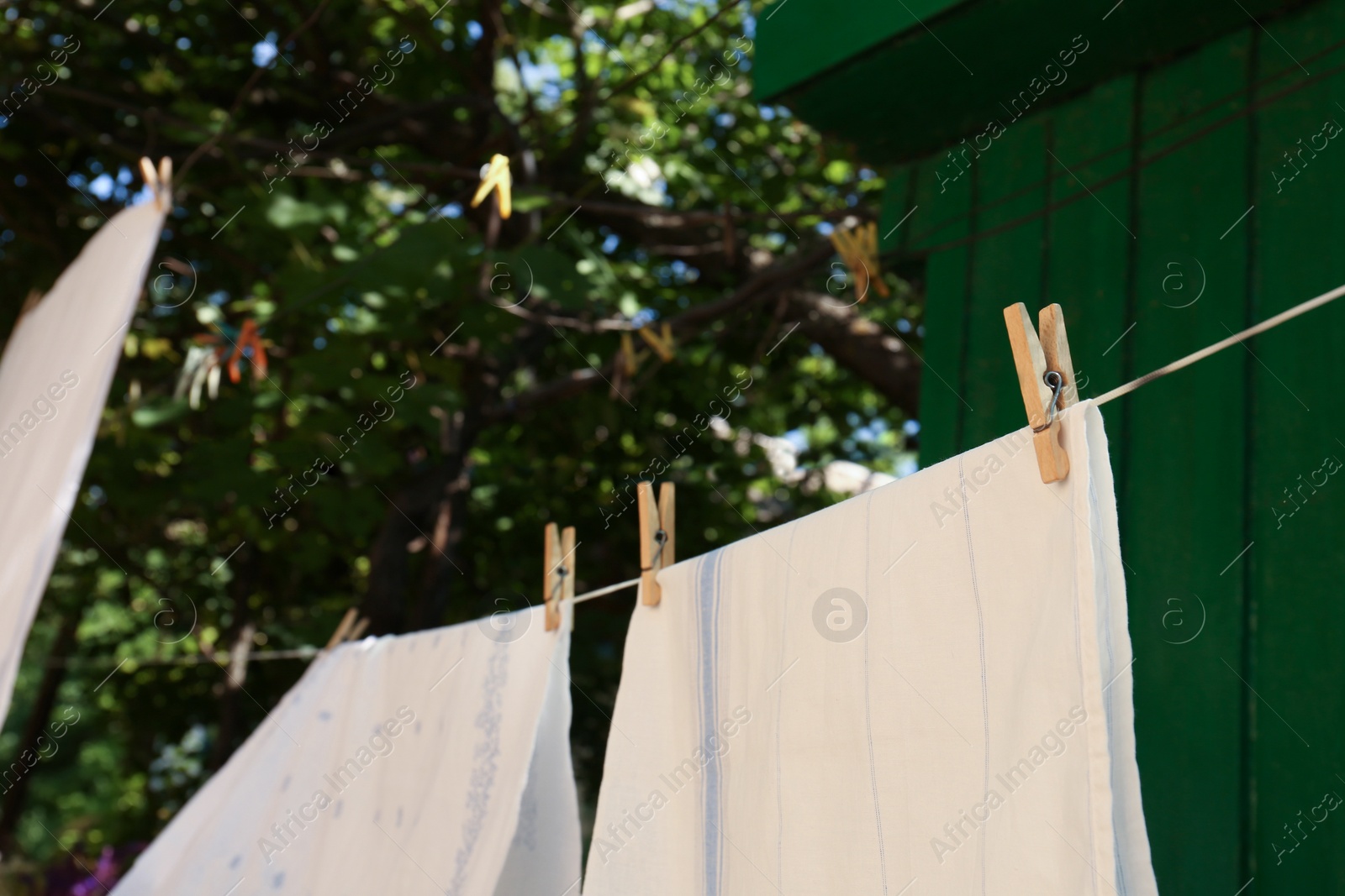 Photo of Washing line with clean laundry and clothespins outdoors