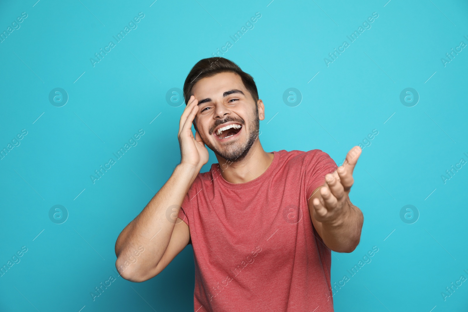 Photo of Handsome young man laughing against color background