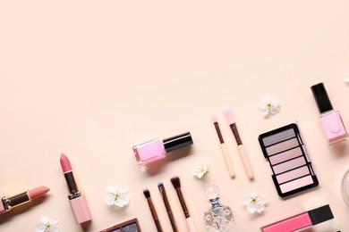 Photo of Flat lay composition with different makeup products and beautiful spring flowers on beige background, space for text