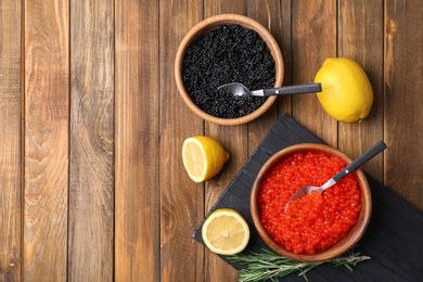 Photo of Bowls with black and red caviar on wooden background