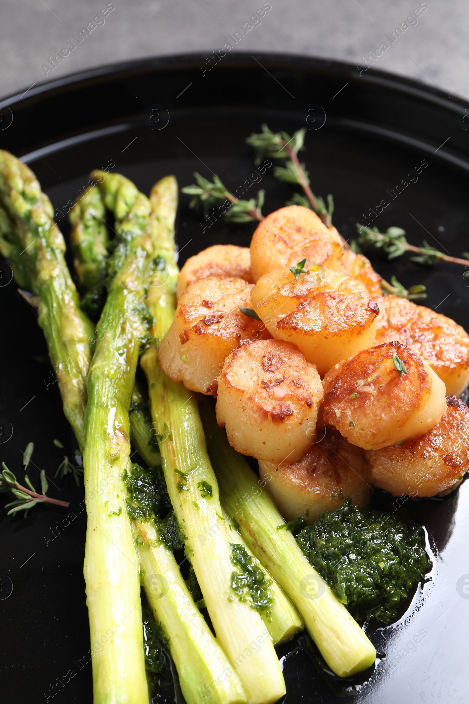 Photo of Delicious fried scallops with asparagus and thyme on plate, closeup