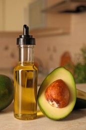 Photo of Fresh avocados and cooking oil on beige marble table in kitchen