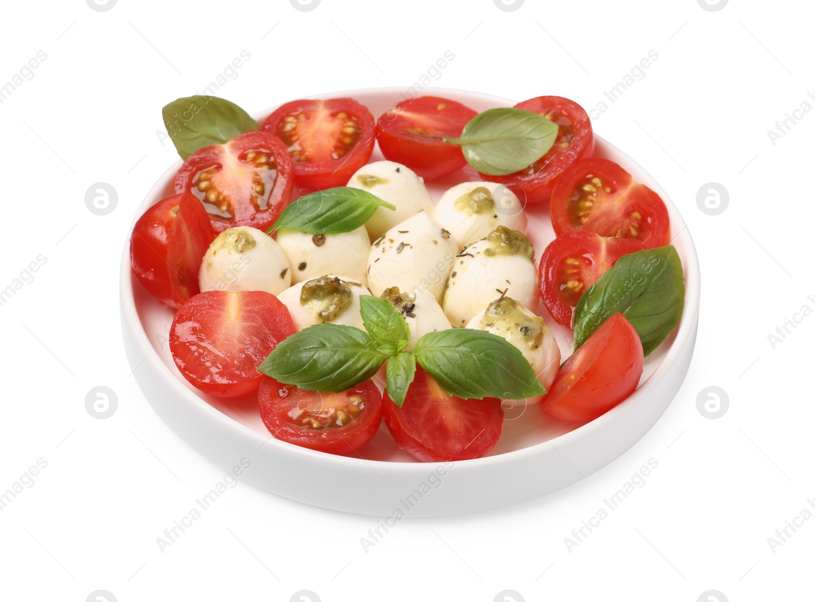 Photo of Plate of tasty Caprese salad with mozzarella, tomatoes, basil and pesto sauce isolated on white