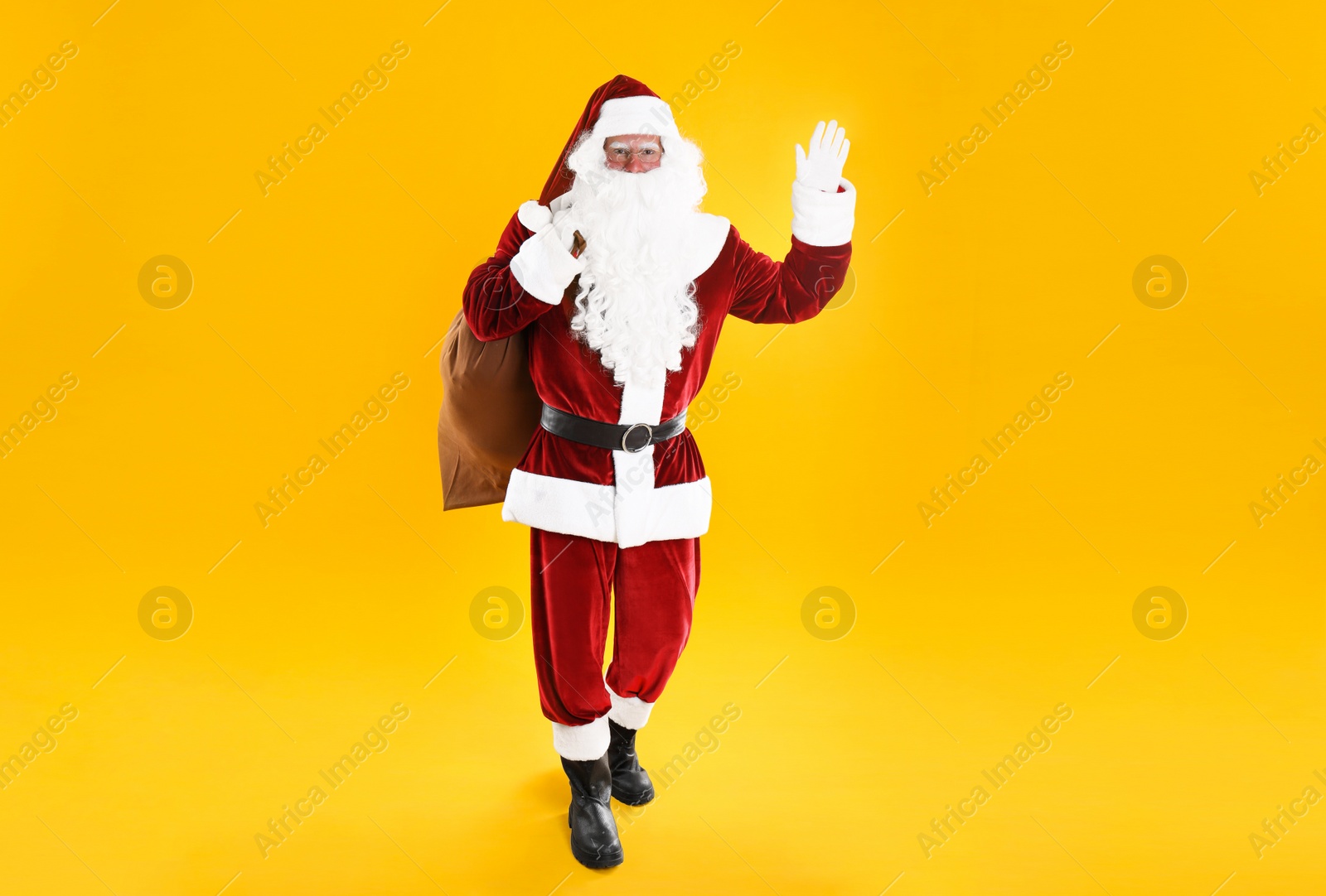 Photo of Full length portrait of Santa Claus with sack on yellow background