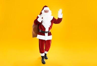 Full length portrait of Santa Claus with sack on yellow background