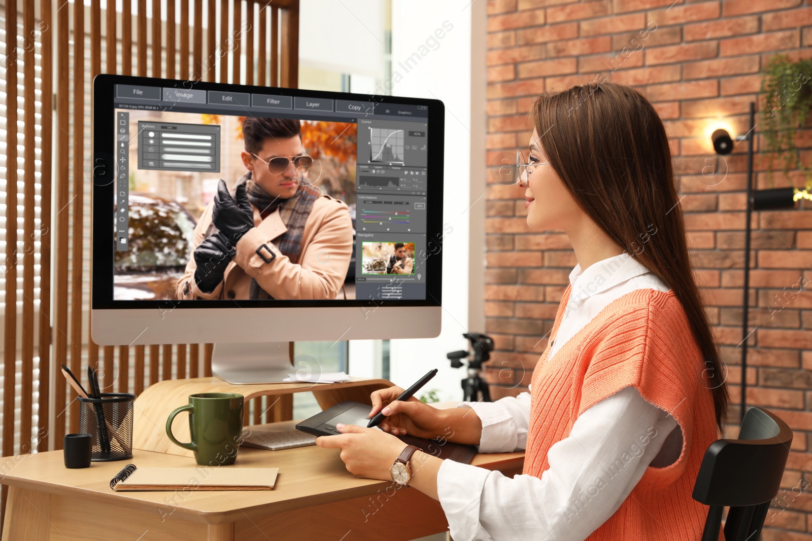 Photo of Professional retoucher working on graphic tablet at desk in office