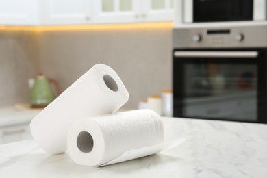 Photo of Rolls of paper towels on white marble table in kitchen. Space for text