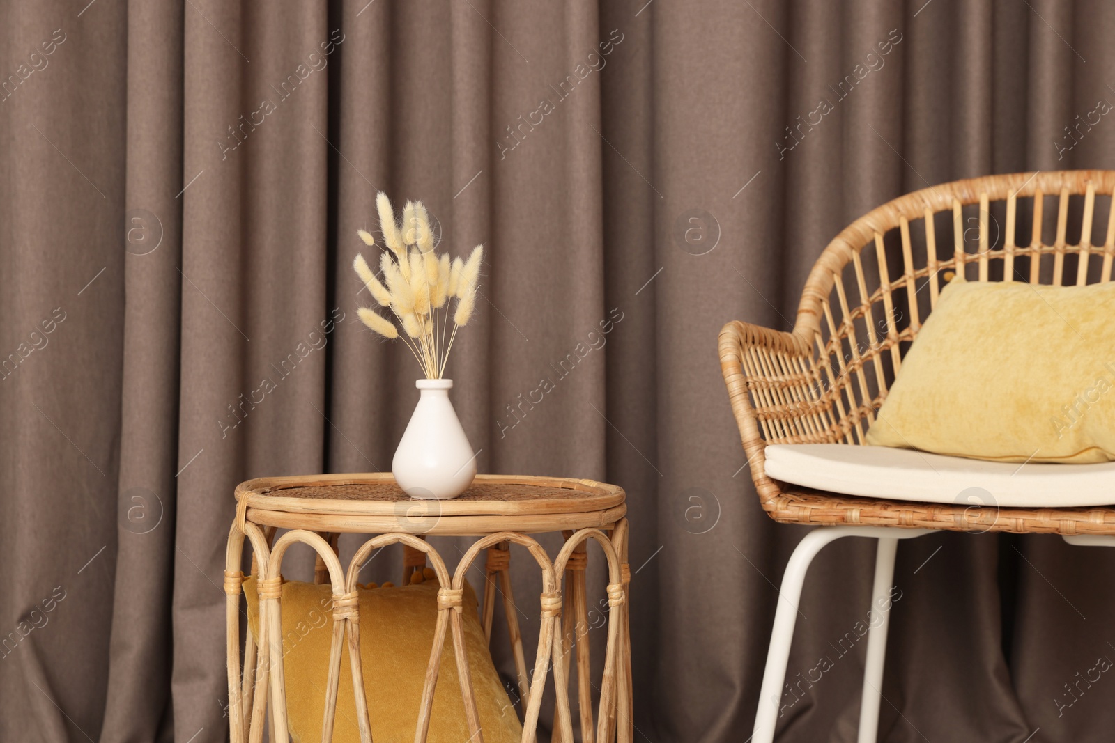 Photo of Armchair and wicker table with vase near elegant curtains indoors