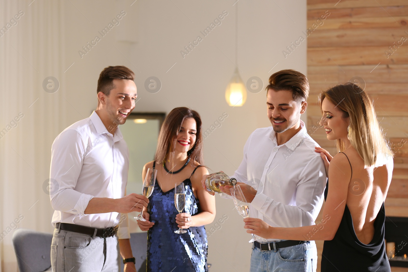 Photo of Man pouring friends champagne at festive party indoors