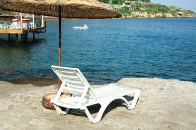 Photo of Lounge chair and beach umbrella on sea shore