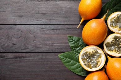 Delicious ripe granadillas and leaves on wooden table, flat lay. Space for text