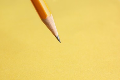 One sharp graphite pencil on yellow background, closeup. Space for text