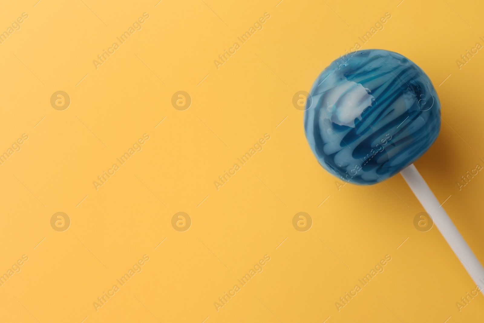 Photo of Tasty lollipop on orange background, top view. Space for text