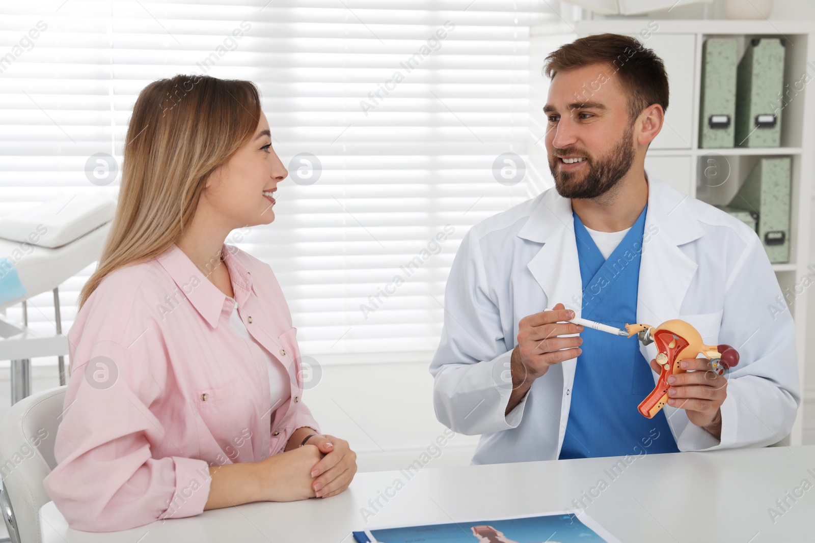 Photo of Gynecologist demonstrating model of female reproductive system to young woman in clinic