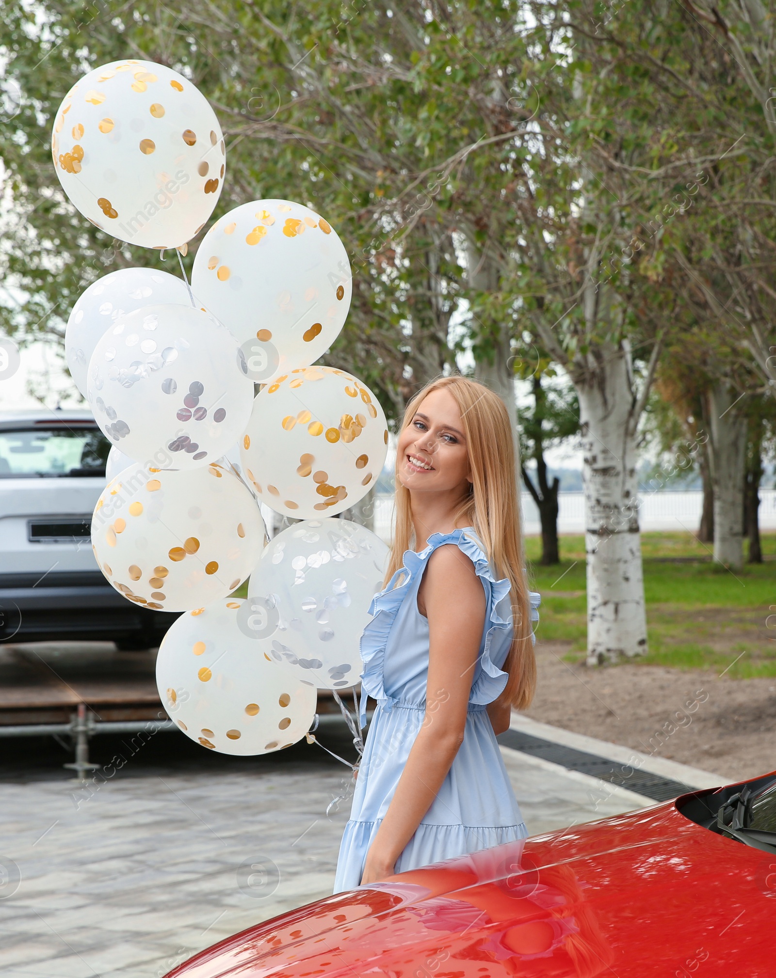 Photo of Beautiful young woman with bunch of balloons outdoors