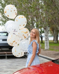 Photo of Beautiful young woman with bunch of balloons outdoors