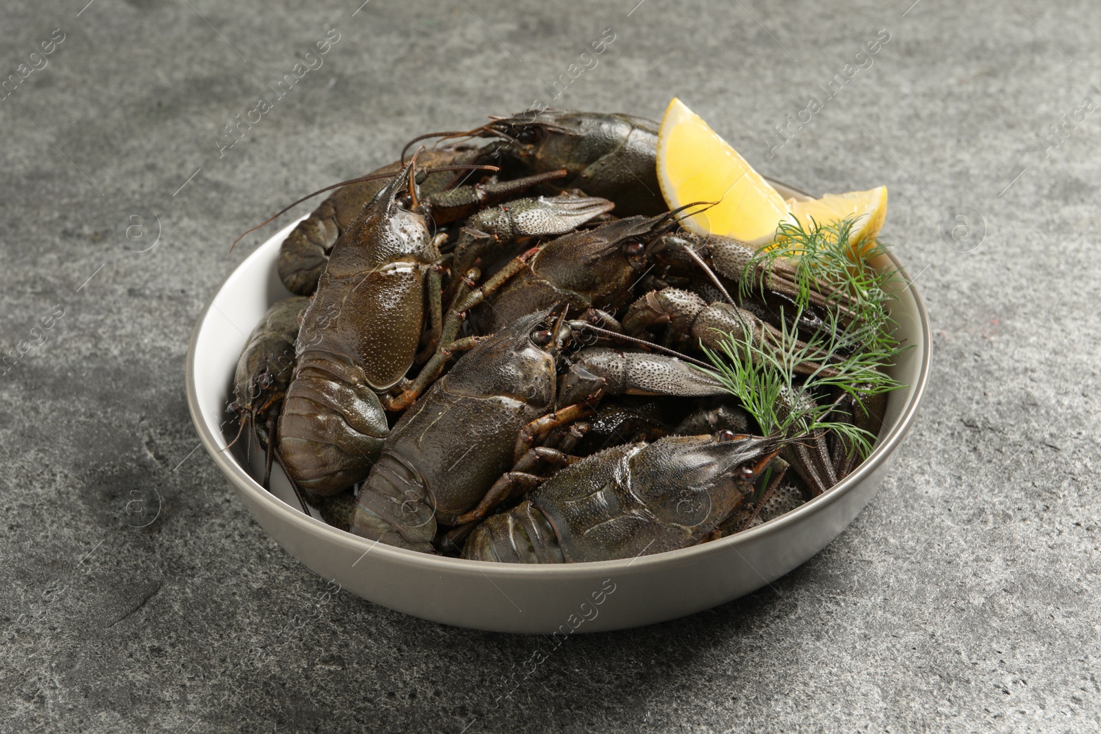 Photo of Fresh raw crayfishes with lemon and dill on grey table