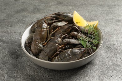 Photo of Fresh raw crayfishes with lemon and dill on grey table