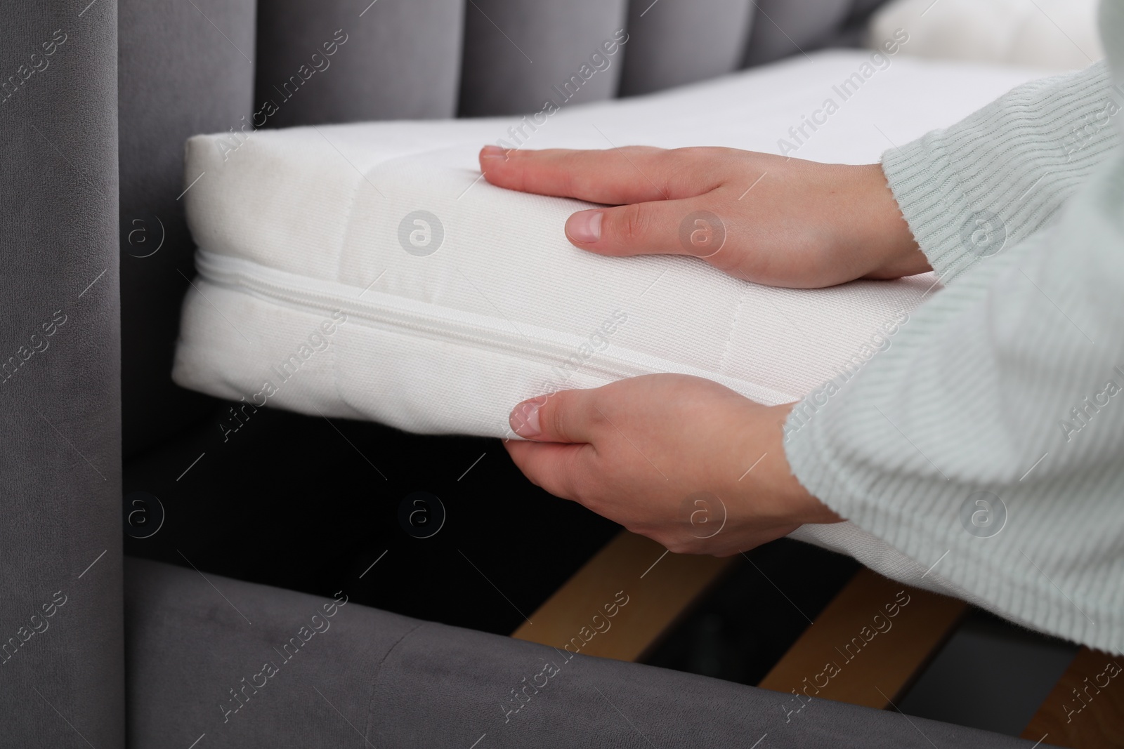 Photo of Woman putting new soft mattress on bed, closeup