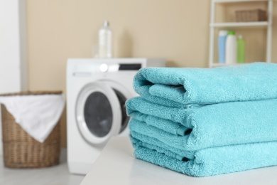 Stack of clean soft towels on table in laundry room. Space for text