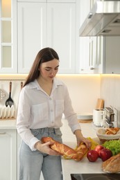 Photo of Woman with baguette and other products in kitchen