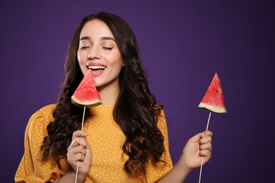 Photo of Beautiful young woman with pieces of watermelon on purple background