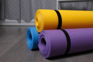 Photo of Bright rolled camping mats on grey wooden floor indoors, closeup