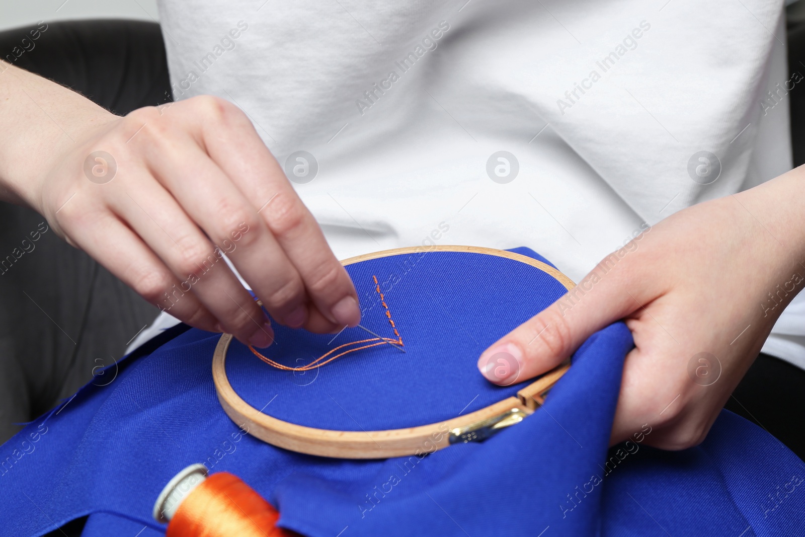 Photo of Woman with sewing needle and thread embroidering on cloth, closeup