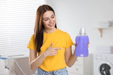 Photo of Beautiful woman showing fabric softener in bathroom