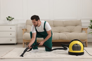 Photo of Dry cleaner's employee hoovering carpet with vacuum cleaner in room