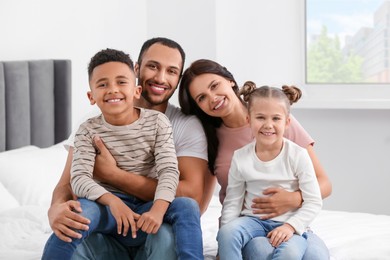 Happy international family spending time together on bed at home