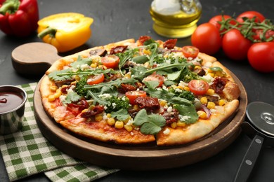 Photo of Delicious vegetarian pizza, ingredients and cutter on black table