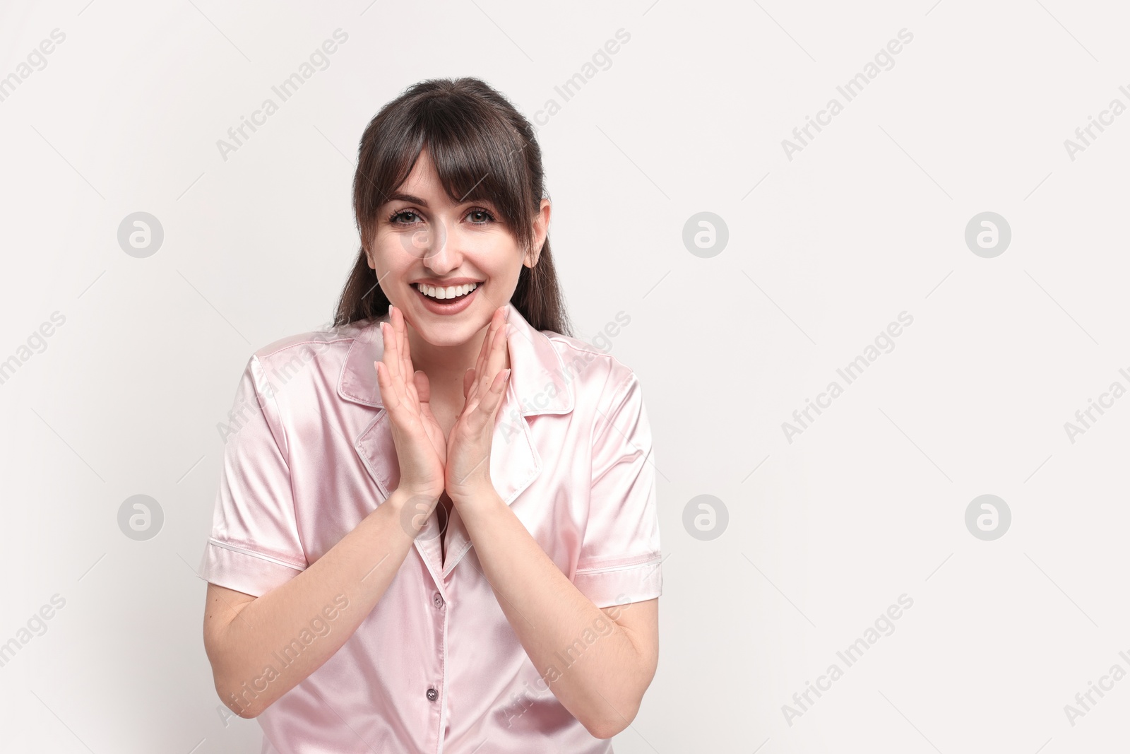 Photo of Happy woman in pyjama on light grey background, space for text