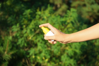 Photo of Woman holding insect repellent outdoors, closeup view
