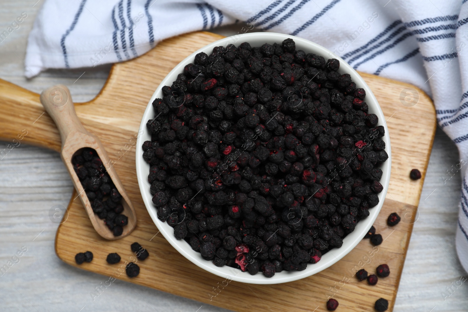 Photo of Bowl and scoop with dried blueberries on white wooden table, top view