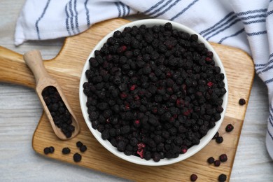 Bowl and scoop with dried blueberries on white wooden table, top view